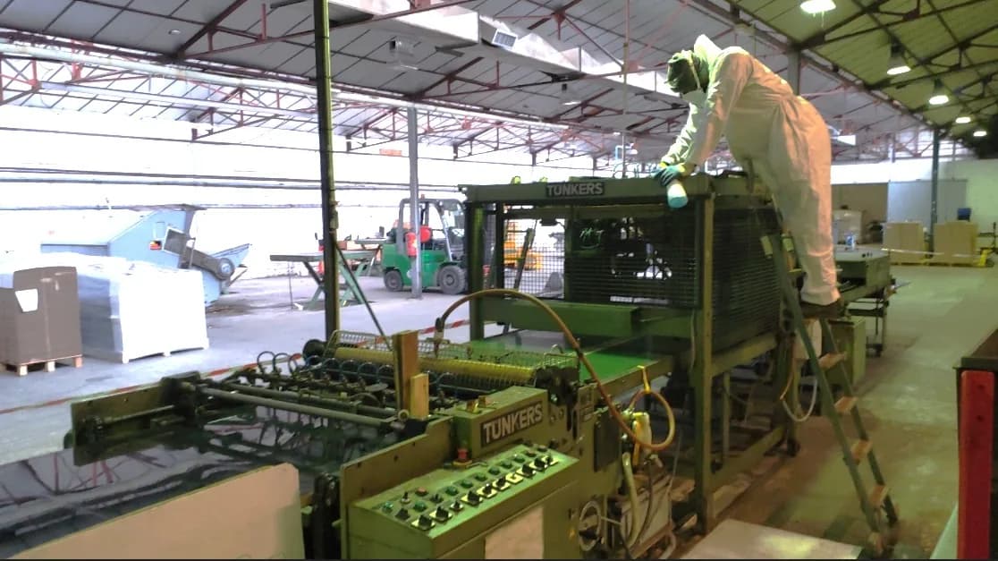 Technicien en combinaison intervenant sur une ligne de production industrielle
